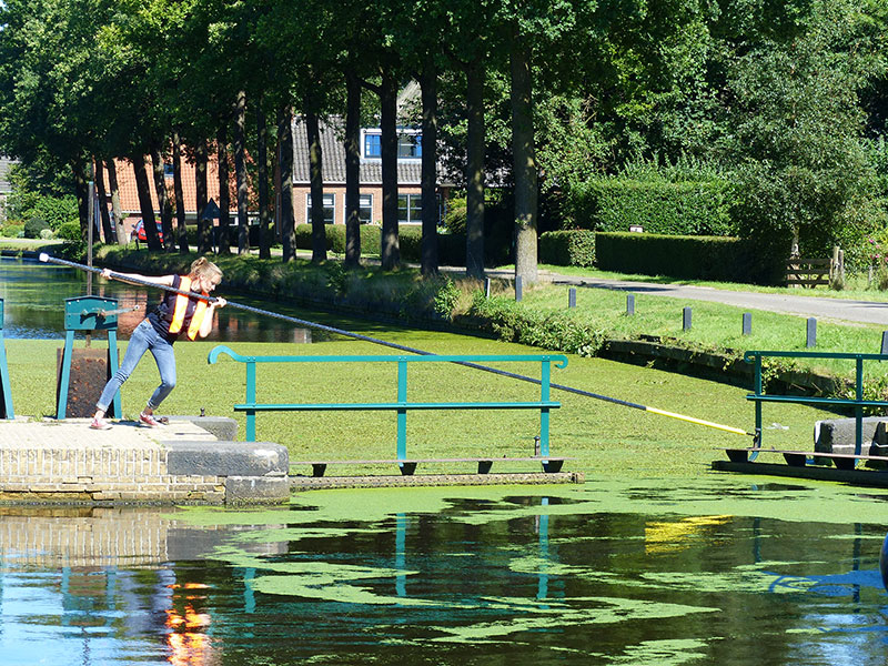 De groene sluizen van Lippenhuizen en Wijnjeterp. Sluiswachters hengelen de waterplanten uit de kolk. Fotografie: Jana Hendriks, Friesland Holland Nieuwsdienst.