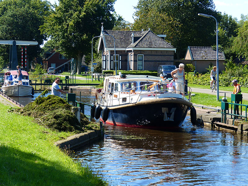 De groene sluizen van Lippenhuizen en Wijnjeterp. Sluiswachters hengelen de waterplanten uit de kolk. Fotografie: Jana Hendriks, Friesland Holland Nieuwsdienst.